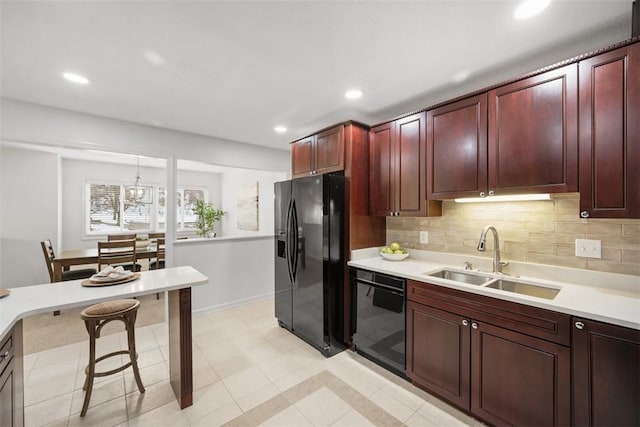 kitchen featuring decorative light fixtures, tasteful backsplash, sink, and black appliances