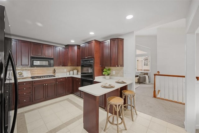 kitchen with black appliances, a kitchen breakfast bar, decorative backsplash, light colored carpet, and kitchen peninsula