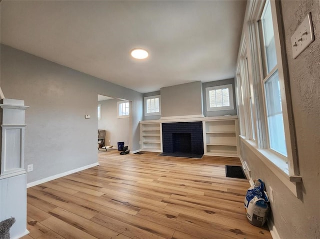 unfurnished living room featuring a brick fireplace and light wood-type flooring