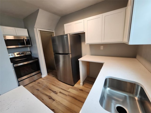 kitchen with sink, light wood-type flooring, white cabinets, and appliances with stainless steel finishes