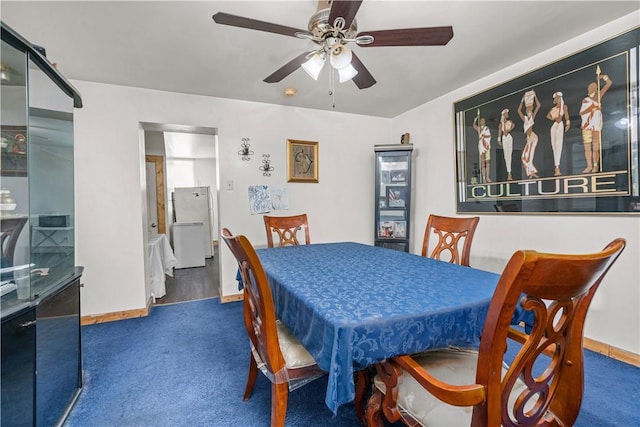 dining area with ceiling fan and dark carpet