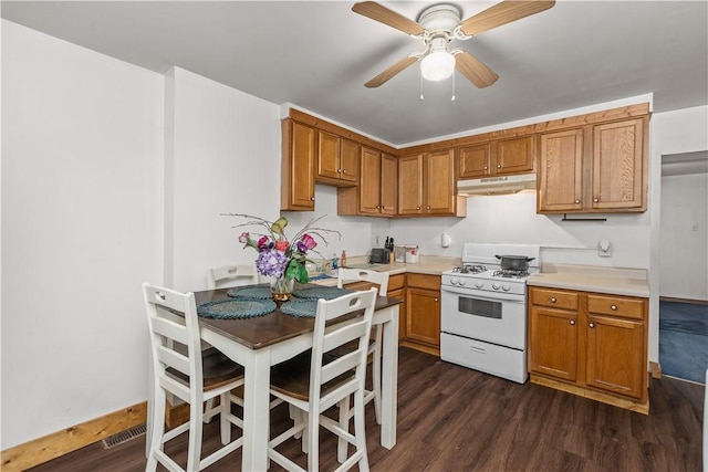 kitchen featuring white gas range, dark wood-type flooring, and ceiling fan