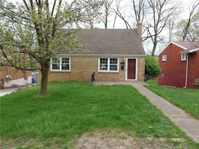 cape cod home with brick siding, a front yard, a shingled roof, and a chimney