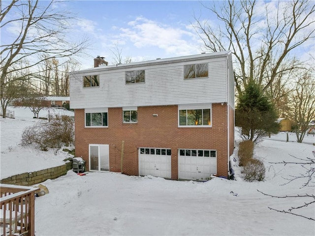 snow covered back of property with a garage