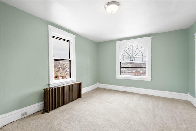 spare room with radiator and light carpet