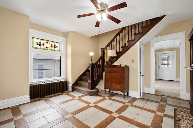 staircase with radiator heating unit, tile patterned floors, ceiling fan, and plenty of natural light