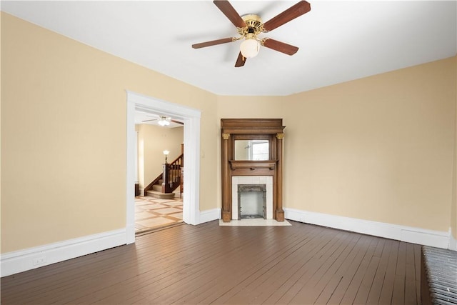 unfurnished living room featuring ceiling fan, dark hardwood / wood-style floors, and a fireplace