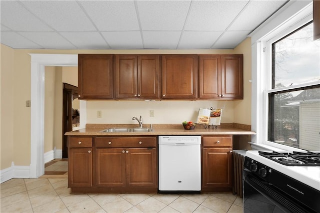 kitchen with range with gas cooktop, sink, light tile patterned floors, white dishwasher, and a drop ceiling