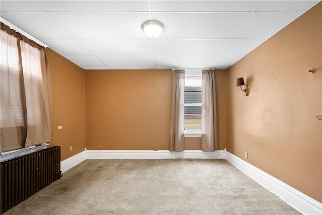 spare room with radiator, carpet floors, and a paneled ceiling