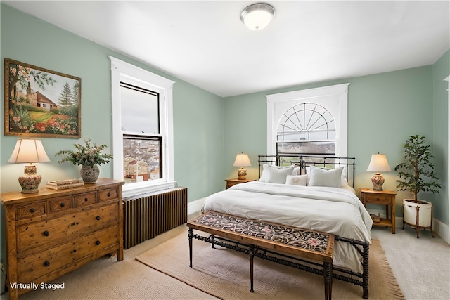 bedroom featuring radiator, light carpet, and multiple windows