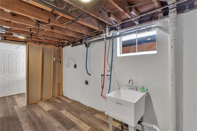 basement with hardwood / wood-style flooring and sink