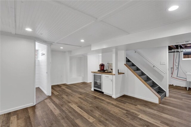 basement featuring dark wood-type flooring, beverage cooler, and indoor bar