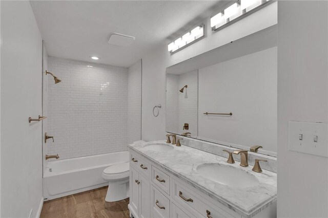 full bathroom with tiled shower / bath, vanity, and toilet