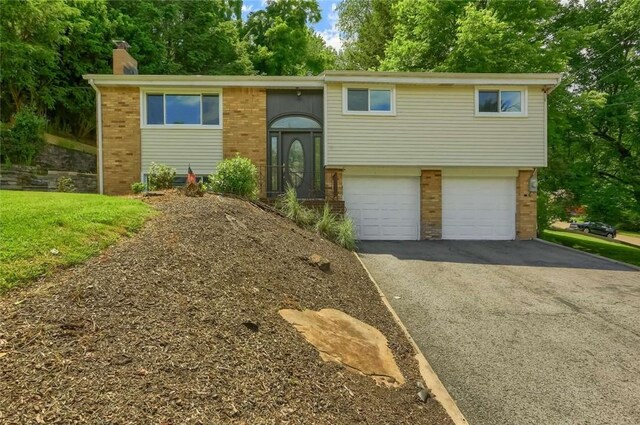 217 Belladonna Dr, Shaler, PA 15116 - bi-level home with brick siding, asphalt driveway, a chimney, and an attached garage