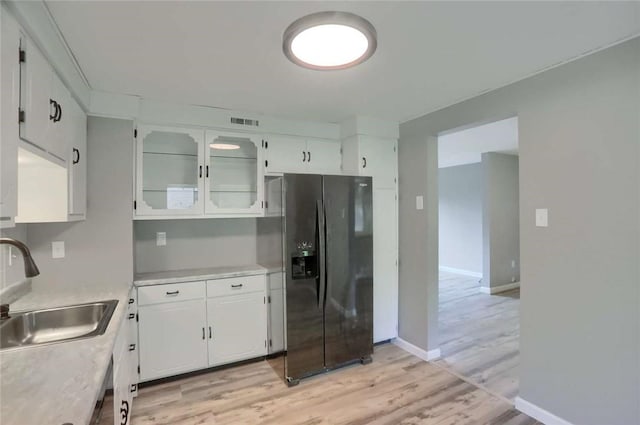 217 Belladonna Dr, Shaler, PA 15116 - kitchen featuring black fridge with ice dispenser, light countertops, light wood finished floors, white cabinets, and glass insert cabinets