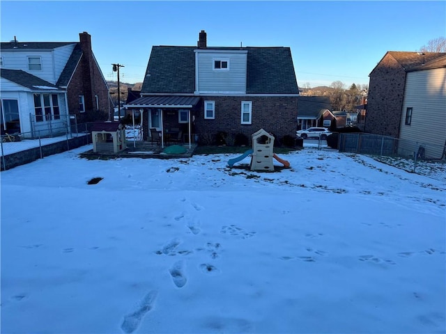 snow covered rear of property featuring a playground