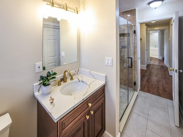 bathroom featuring vanity, toilet, tile patterned flooring, and a shower with door