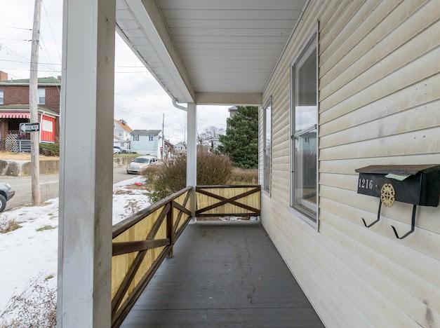 snow covered back of property with covered porch