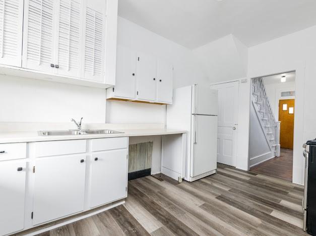 kitchen with white cabinetry, dark hardwood / wood-style floors, sink, and white fridge