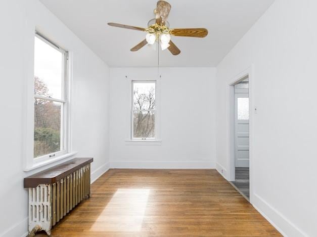 unfurnished room with ceiling fan, radiator heating unit, and light hardwood / wood-style floors