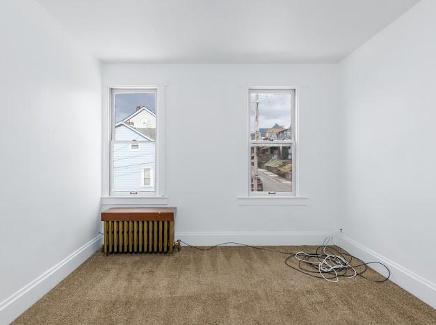 carpeted empty room with radiator heating unit