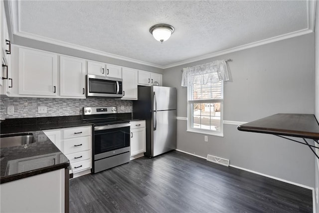 kitchen with crown molding, dark wood-type flooring, appliances with stainless steel finishes, white cabinetry, and decorative backsplash