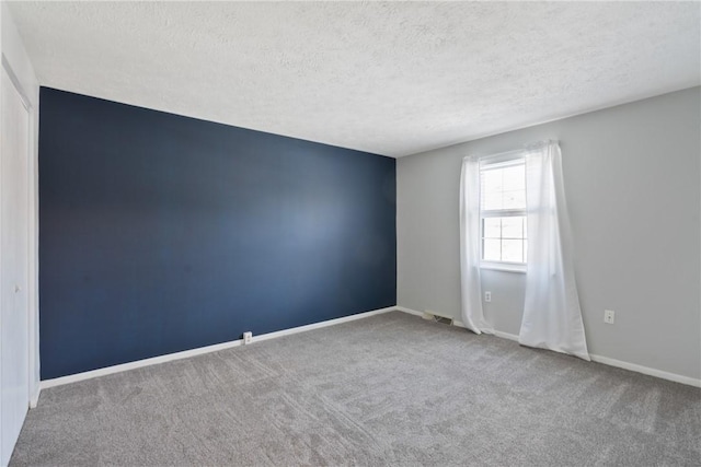 empty room with carpet floors and a textured ceiling