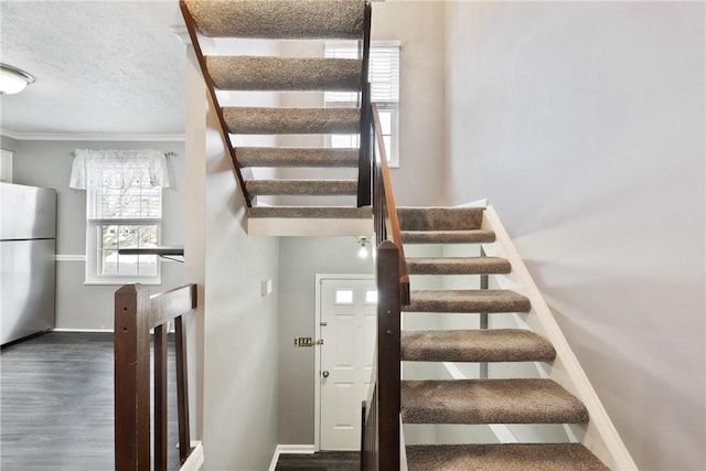 staircase featuring wood-type flooring, crown molding, and a textured ceiling