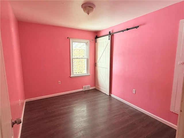 unfurnished room featuring a barn door and dark hardwood / wood-style flooring