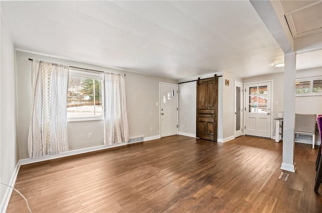 unfurnished living room featuring dark hardwood / wood-style floors and a barn door