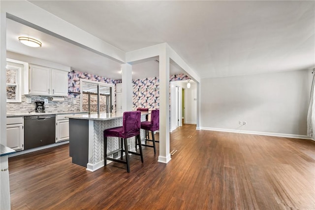 kitchen featuring tasteful backsplash, black dishwasher, white cabinets, a kitchen breakfast bar, and dark wood-type flooring