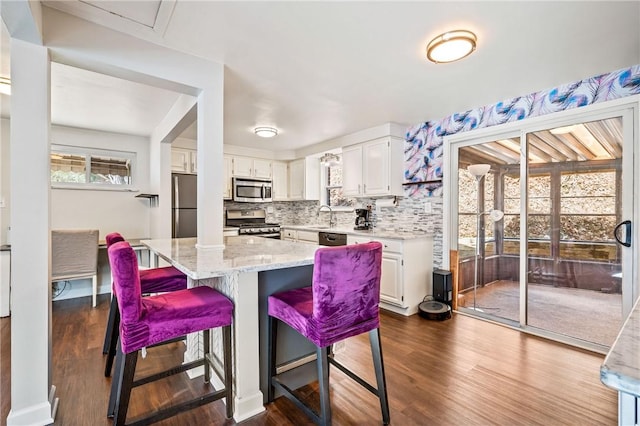 kitchen with white cabinetry, light stone counters, dark hardwood / wood-style flooring, and stainless steel appliances