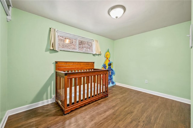 bedroom with dark hardwood / wood-style flooring and a nursery area