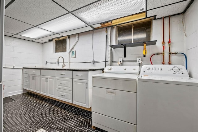 clothes washing area with separate washer and dryer, sink, and cabinets