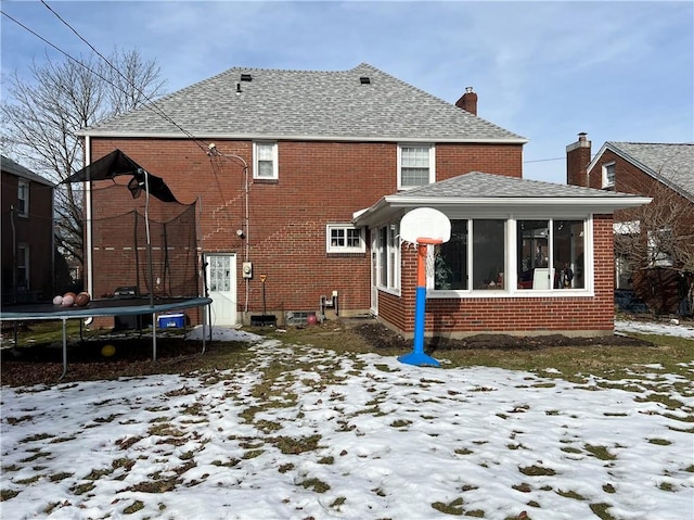 snow covered property with a sunroom and a trampoline