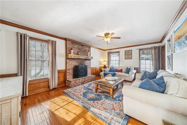 living room featuring hardwood / wood-style flooring, ceiling fan, ornamental molding, and a brick fireplace