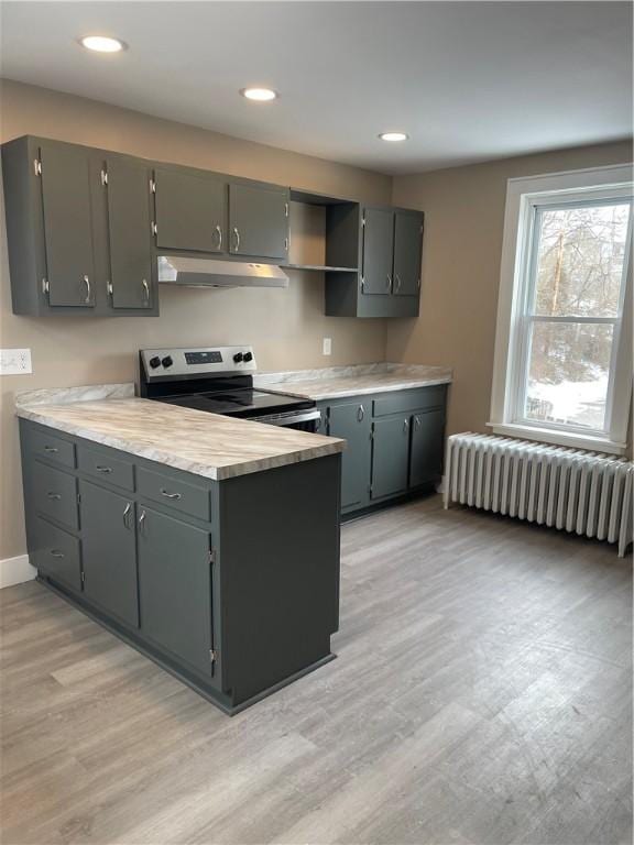 kitchen with electric range, under cabinet range hood, open shelves, radiator heating unit, and light countertops