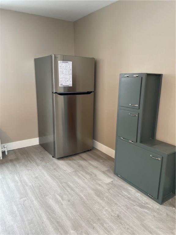 kitchen with light wood-style flooring, freestanding refrigerator, and baseboards