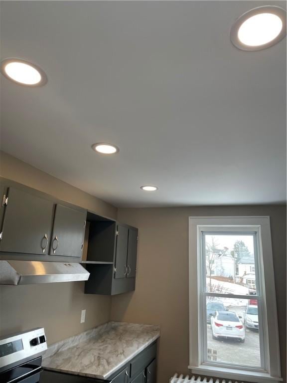 kitchen featuring recessed lighting, gray cabinetry, stove, light countertops, and under cabinet range hood