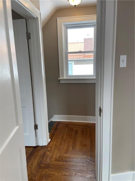 corridor featuring baseboards and vaulted ceiling