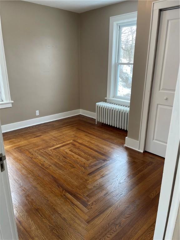 empty room featuring radiator and baseboards