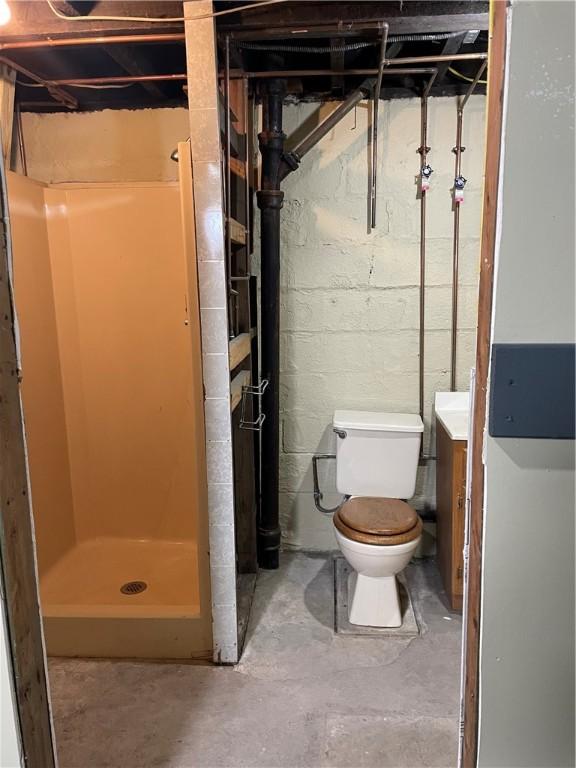 bathroom with vanity, a shower stall, toilet, and concrete floors