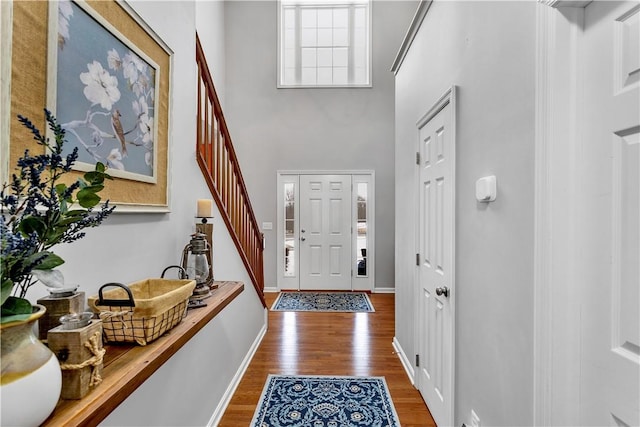 foyer featuring wood-type flooring and a towering ceiling