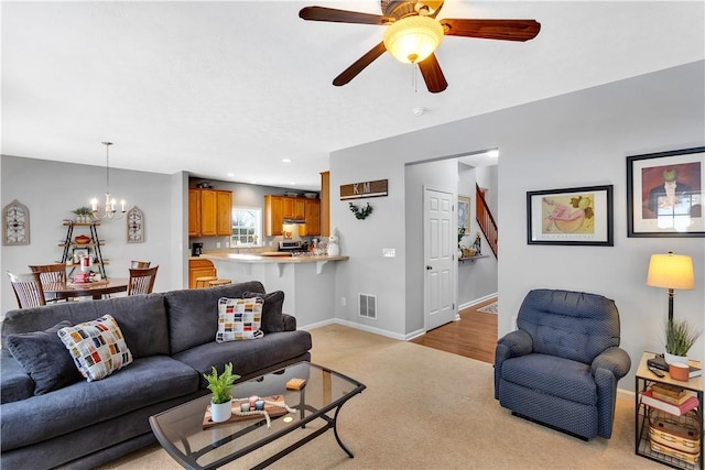 carpeted living room featuring ceiling fan with notable chandelier