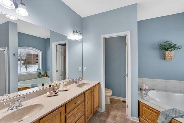 bathroom with a relaxing tiled tub, vanity, toilet, and tile patterned flooring