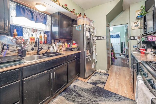 kitchen featuring tasteful backsplash, sink, stainless steel appliances, and light hardwood / wood-style floors