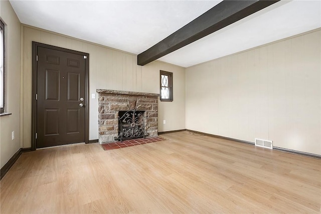 unfurnished living room featuring hardwood / wood-style flooring, a stone fireplace, and beamed ceiling