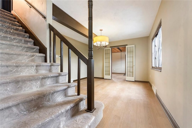 stairs with an inviting chandelier and wood-type flooring