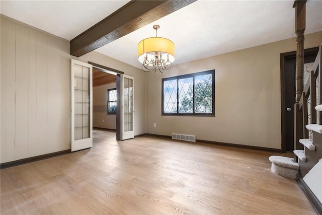 empty room featuring a notable chandelier, french doors, beamed ceiling, and light wood-type flooring