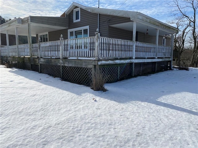 snow covered rear of property featuring covered porch